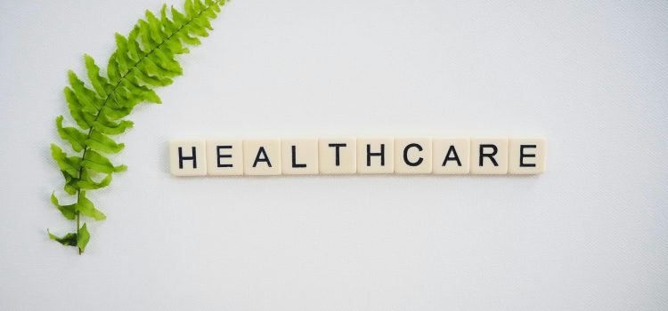 Minimalist health and wellness concept featuring a green fern leaf beside the word "Healthcare" on letter tiles, symbolizing preventive healthcare, healthy living, fitness, and overall wellness.